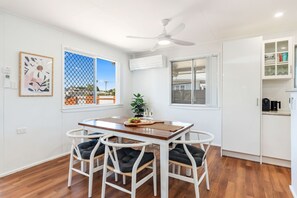 A dining area with a table and chairs, a ceiling fan, and a view through a window. - Ideal for Tradies. BBQ, WiFi, Pet friendly (Torquay)