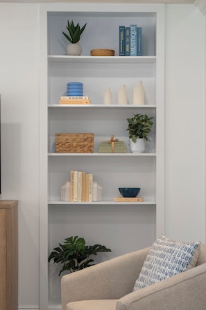 A bookshelf with books, decorative items, and a plant. - Disney, Heated Pool, Game Rm, Fire Pit, King Bed- Getaway Retreat (Hacienda Heights)