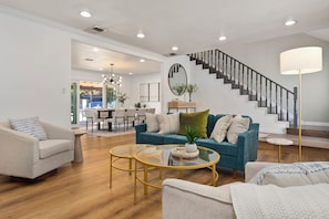 A spacious living room with a staircase, a dining area, and a view of the outdoors. - Disney, Heated Pool, Game Rm, Fire Pit, King Bed- Getaway Retreat (Hacienda Heights)