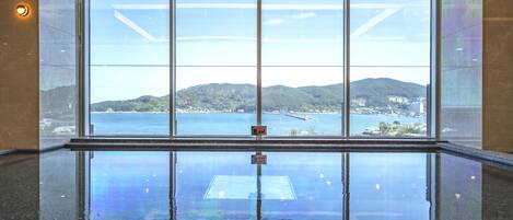 A large, clear window with a view of a body of water and hills.