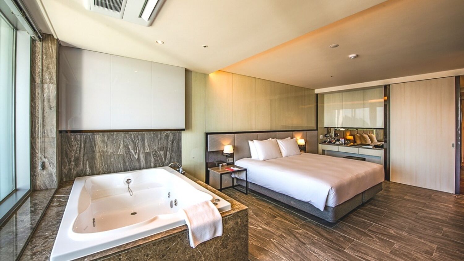 Una camera d'albergo moderna con un letto grande, bagno separato con vasca e cabina armadio.