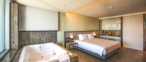 A modern hotel room with a large bed, a separate bathroom with a bathtub, and a walk-in closet.