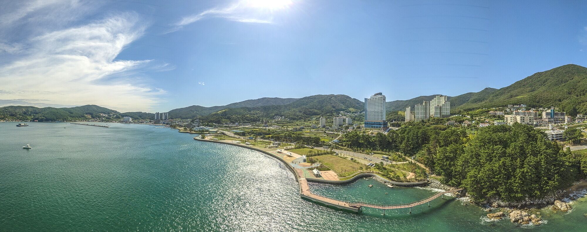 A coastal cityscape with a prominent bridge, buildings, and a clear sky.