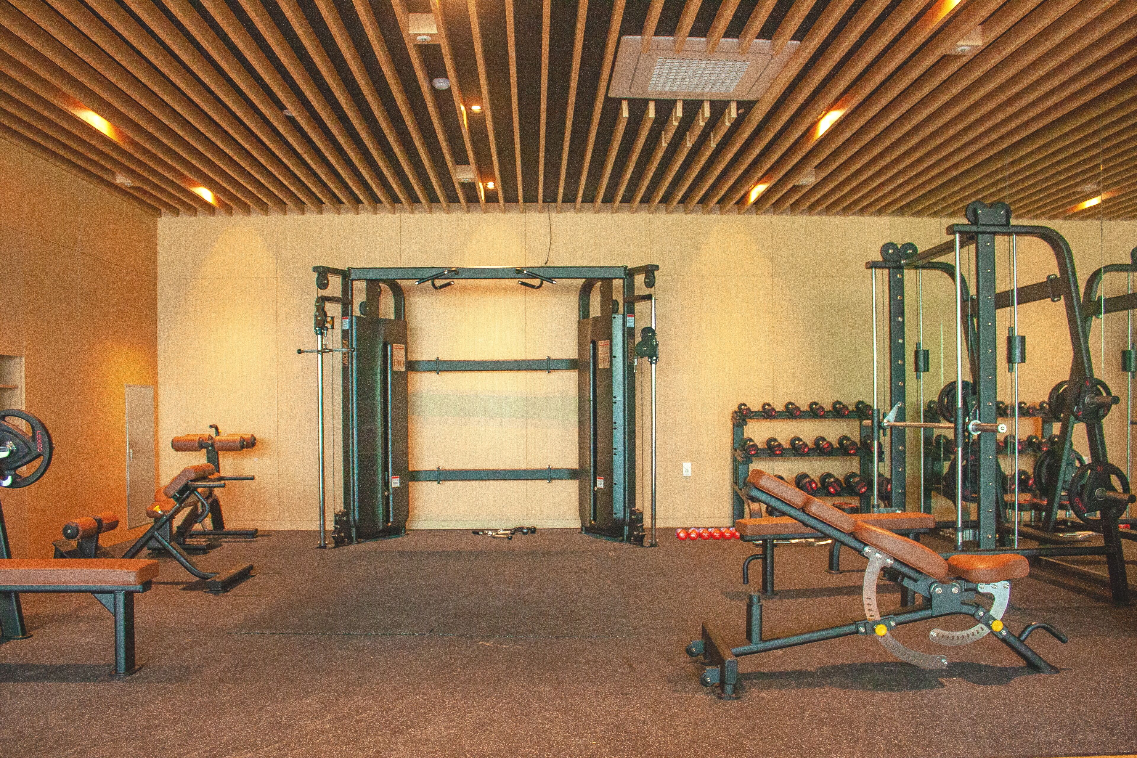 A gym with various exercise equipment, including a squat rack, benches, and weightlifting accessories.