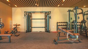 A gym with various exercise equipment, including a squat rack, benches, and weightlifting accessories.