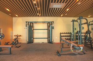 A gym with various exercise equipment, including a squat rack, benches, and weightlifting accessories.