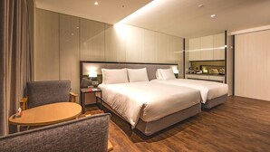 A hotel room with a large bed, a desk, a chair, and a mirror.