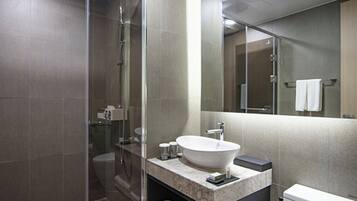 Un baño moderno con ducha envuelta en vidrio, un lavabo blanco y un inodoro.