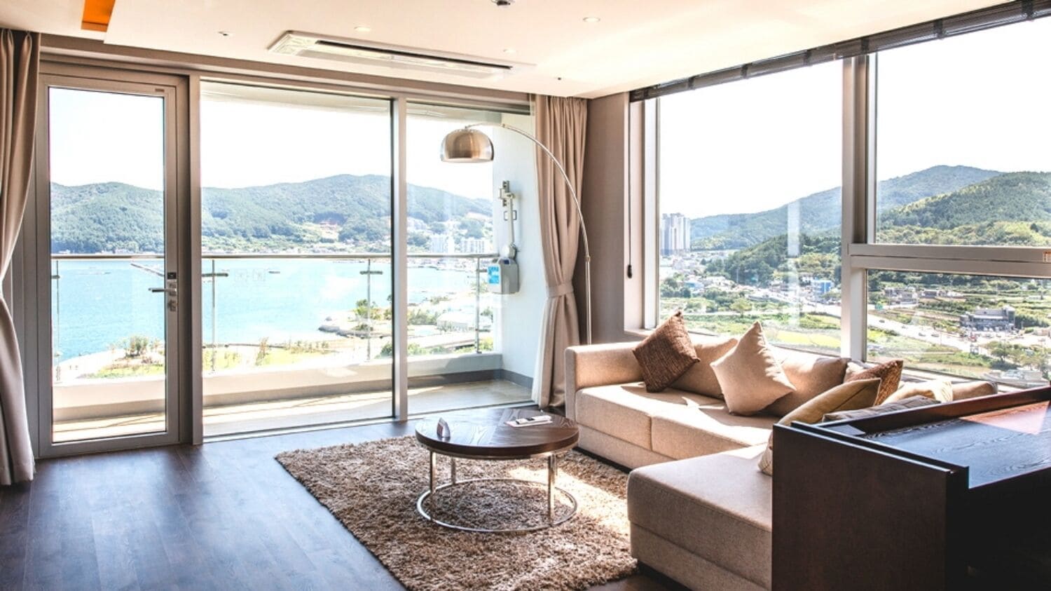 Una sala moderna con sofá, mesa de centro y vistas a un paisaje costero a través de amplios ventanales.