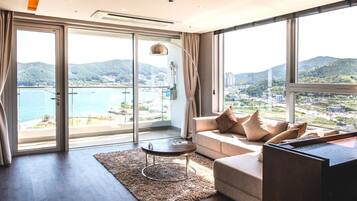 Una sala moderna con sofá, mesa de centro y vistas a un paisaje costero a través de amplios ventanales.
