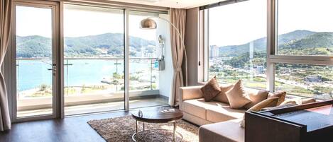 Una sala moderna con sofá, mesa de centro y vistas a un paisaje costero a través de amplios ventanales.
