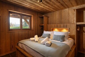 A wooden room with a bed, a window, and a wooden ceiling. - Chalet 1907 (Gérardmer)