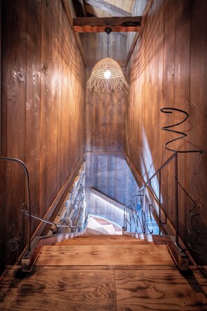 A wooden staircase with a metal spiral railing, leading to a stone wall. - Chalet 1907 (Gérardmer)