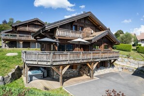 Un chalet en bois doté d’une terrasse, d’un bain à remous extérieur et de fondations en pierre.