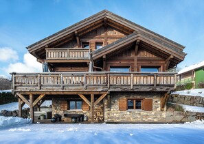 Eine zweistöckige Holzhütte mit Balkon, auf Stein gegründet und mit einem Steinkamin.