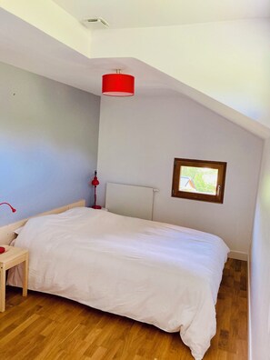 Ein Schlafzimmer mit einem Bett, einer roten Lampe, einem Fenster und einer Deckenleuchte.