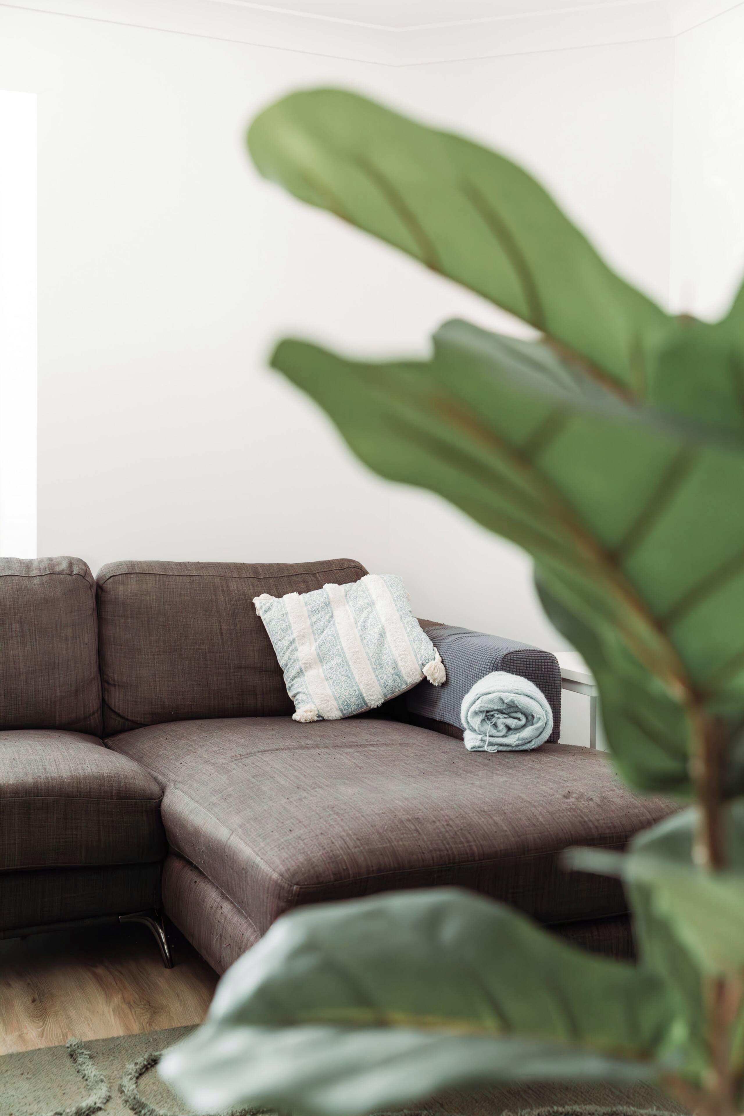 A sectional sofa with a patterned pillow and a rolled-up blanket.
