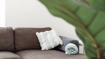 A sectional sofa with a patterned pillow and a rolled-up blanket.