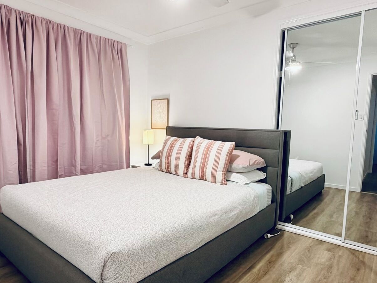 A bedroom with a bed, a bedside table, a lamp, and a sliding door to a bathroom.