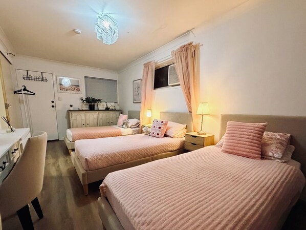 A hotel room with two beds, a desk, and a wardrobe.