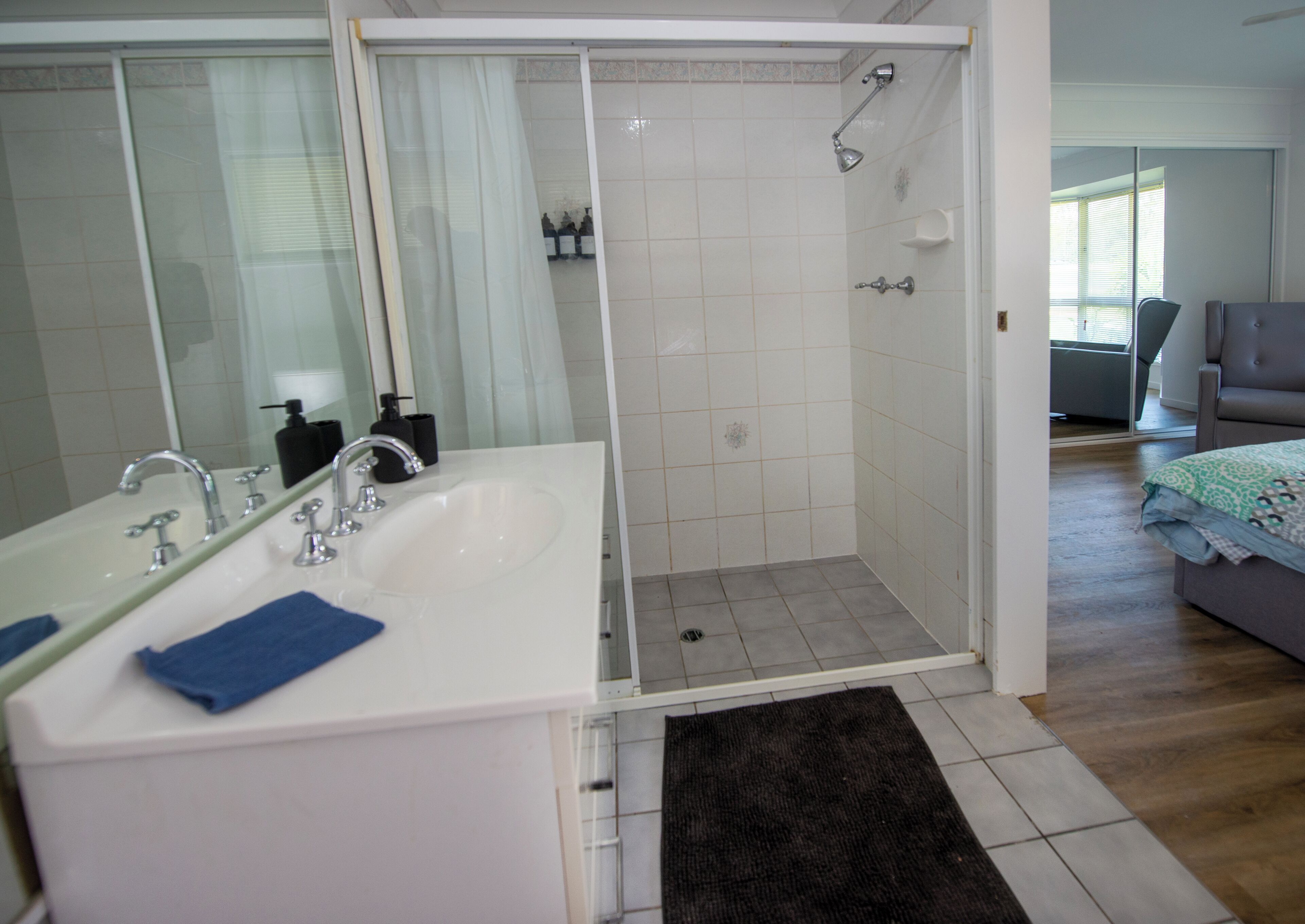 A modern bathroom with a walk-in shower, a large mirror, and a dual sink vanity.