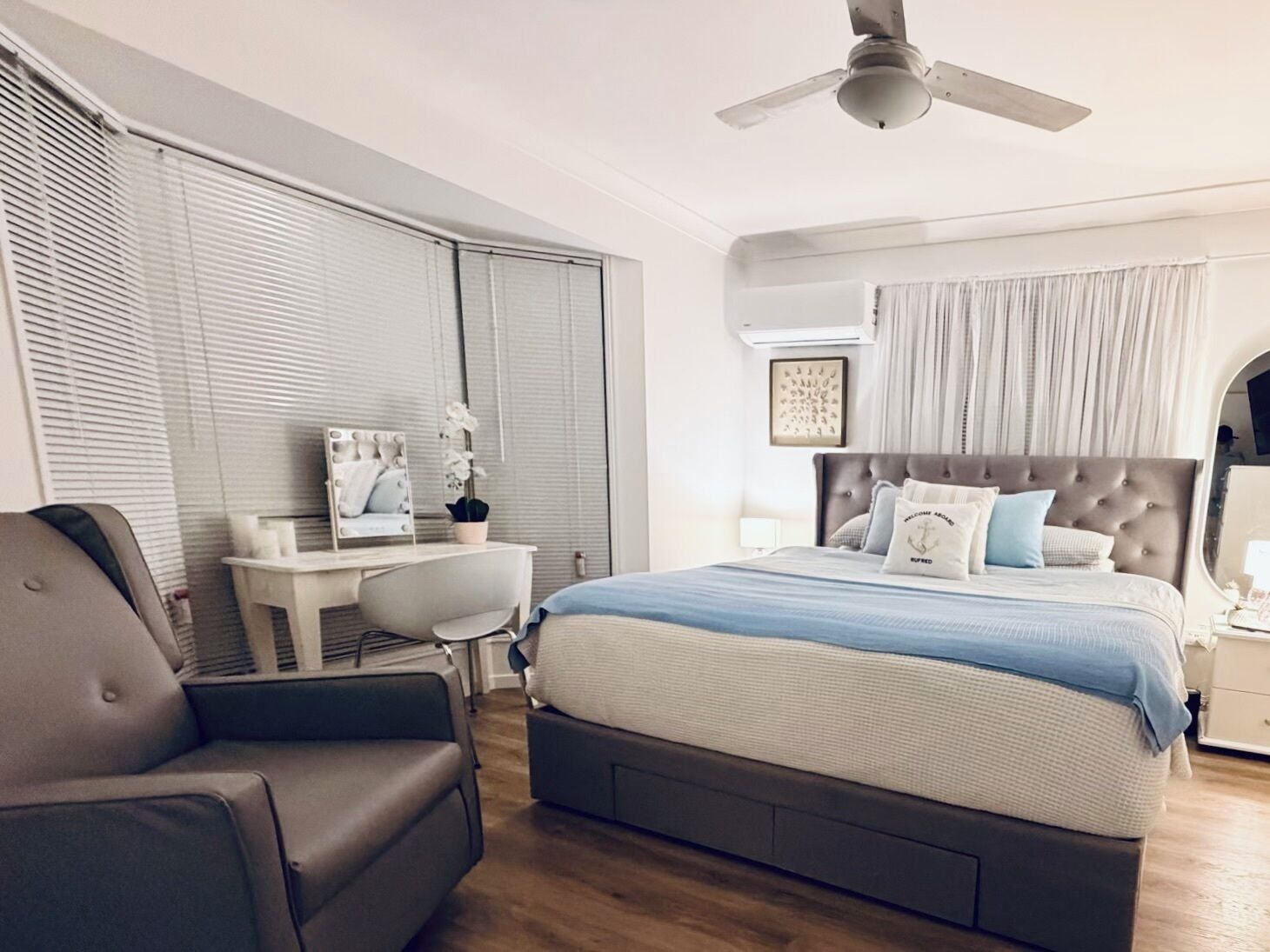A bedroom with a bed, a desk, a chair, and a ceiling fan.