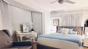 Une chambre à coucher avec un lit, un bureau, une chaise et un ventilateur de plafond.