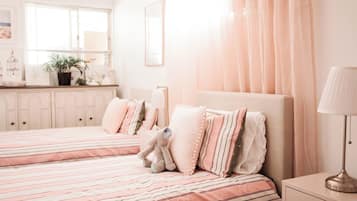 A bedroom with two beds, a nightstand, a lamp, and a window with curtains.