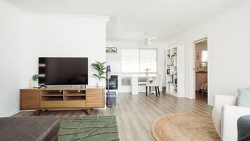 A modern living room with a flat-screen TV, wooden entertainment unit, and a green area rug.