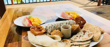 Una mesa de comedor con platos de comida y vista a una piscina.