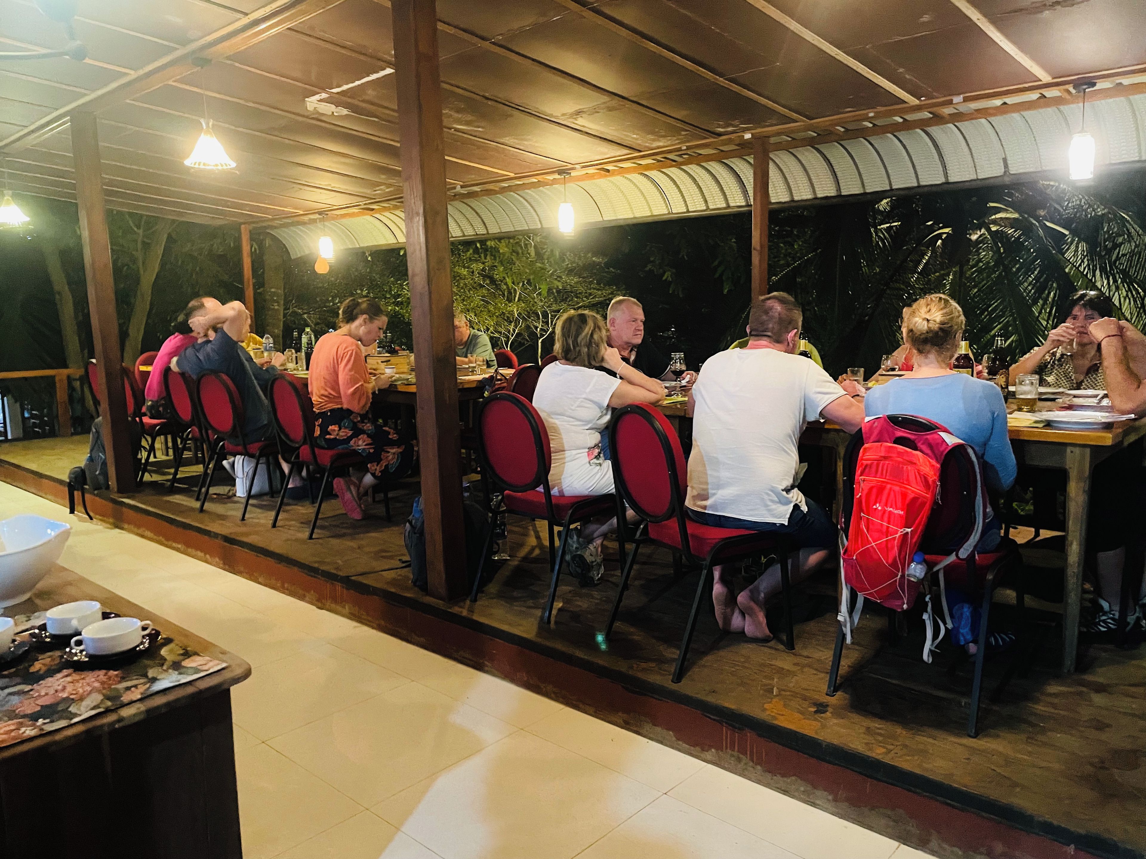 Un área de comedor al aire libre con mesas y sillas, bajo una estructura cubierta con techo curvo.