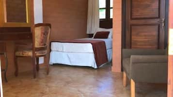 A room with a bed, a chair, a desk, and a door.