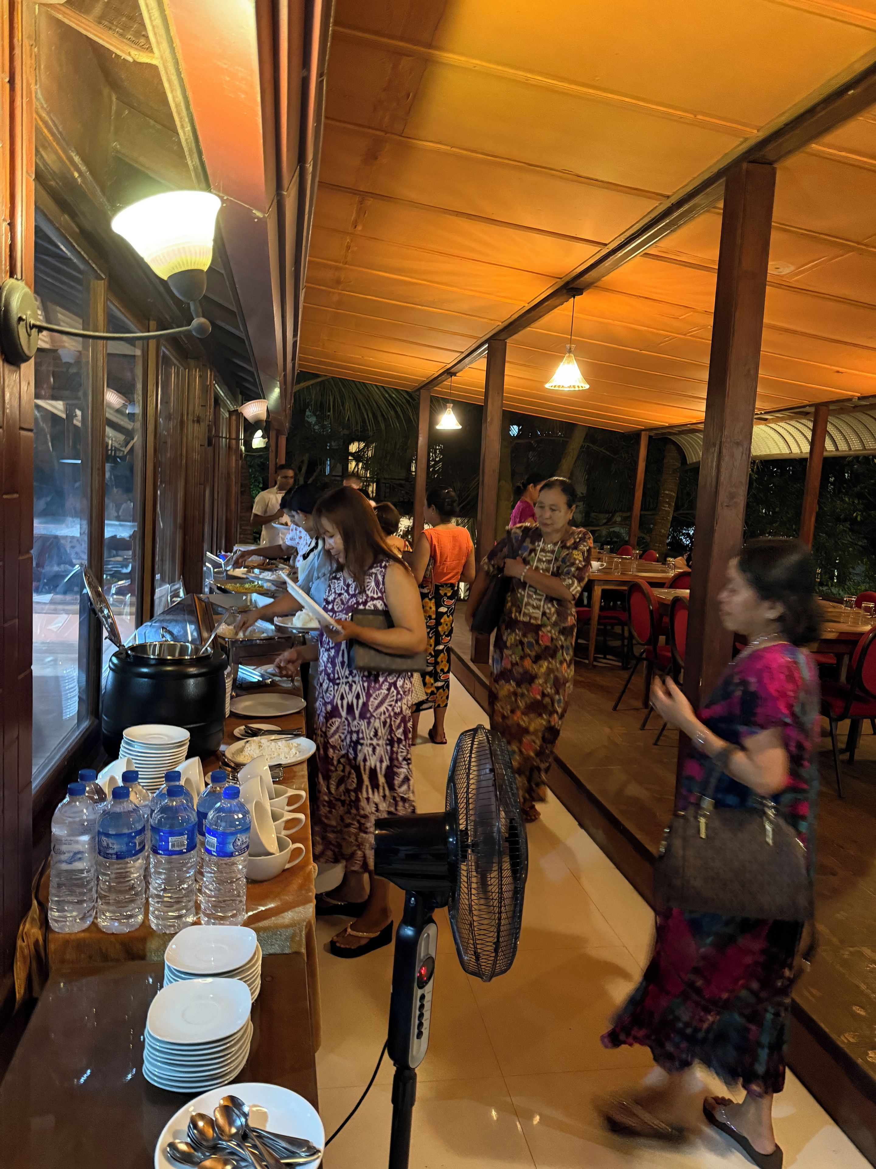 Ein Restaurant mit einer langen Theke, Wasserflaschen und gestapelten Tellern.