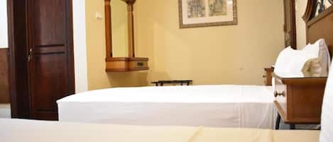 A hotel room with a bed, a wooden dresser, a mirror, and a framed picture on the wall.