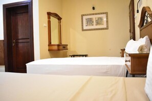 Una habitación de hotel con una cama, un aparador de madera, un espejo y un cuadro en la pared.
