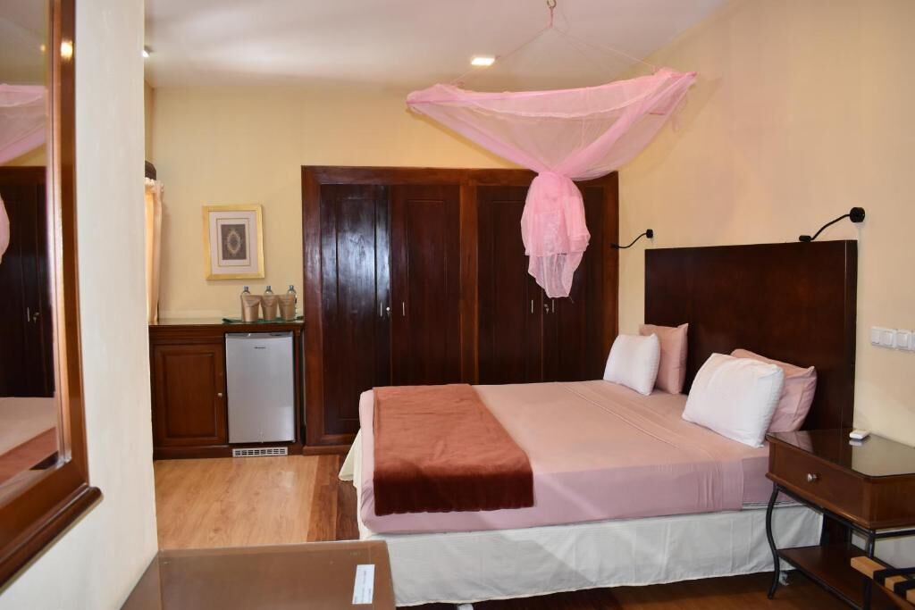 Une chambre avec un lit, une table de chevet, une armoire et un petit coin cuisine.