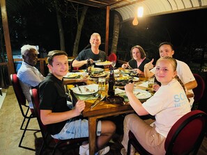 A group of people dining at an outdoor table with various dishes and drinks. - Hotel 4 U Saliya Garden  (Anuradhapura)