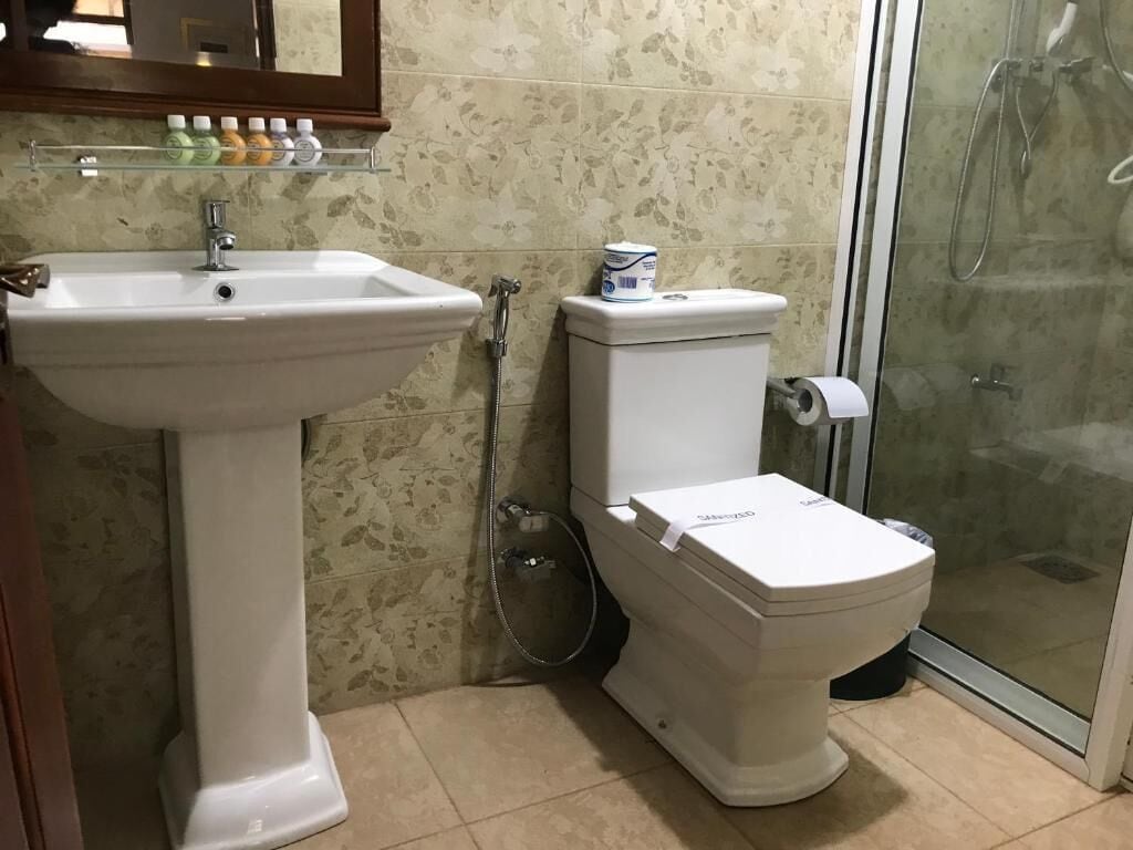 Baño con lavamanos pedestal, inodoro y cabina de ducha de cristal.