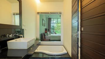 Un baño moderno con una bañera grande, un lavabo independiente y un espejo.