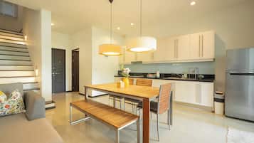 Cocina moderna con comedor, electrodomésticos de acero inoxidable y una escalera que sube a otro nivel.