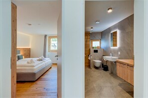 Ein modernes Schlafzimmer mit einem großen Bett und einem Badezimmer mit moderner Waschtisch und Spiegel.