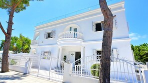 A white multi-story building with balconies, a gated entrance, and a clear sky. - Villa Cecilia Coral - Beautiful Mansion in Coral Bay (Coral Bay)