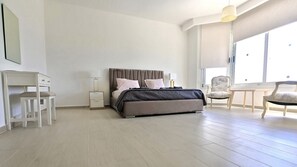 Une chambre moderne avec un grand lit, des tables de chevet, un bureau et une chaise.