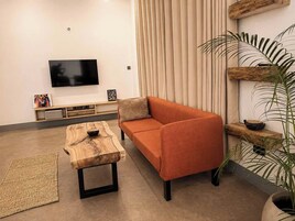 A modern living room with a sofa, a coffee table, a TV, and a plant.