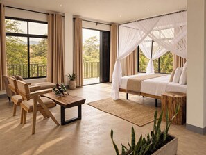 Una camera da letto con un letto, una zona relax con sedie, un tavolino e vista sul verde circostante.