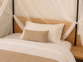 A bed with a wooden headboard, white bedding, and a beige pillow.