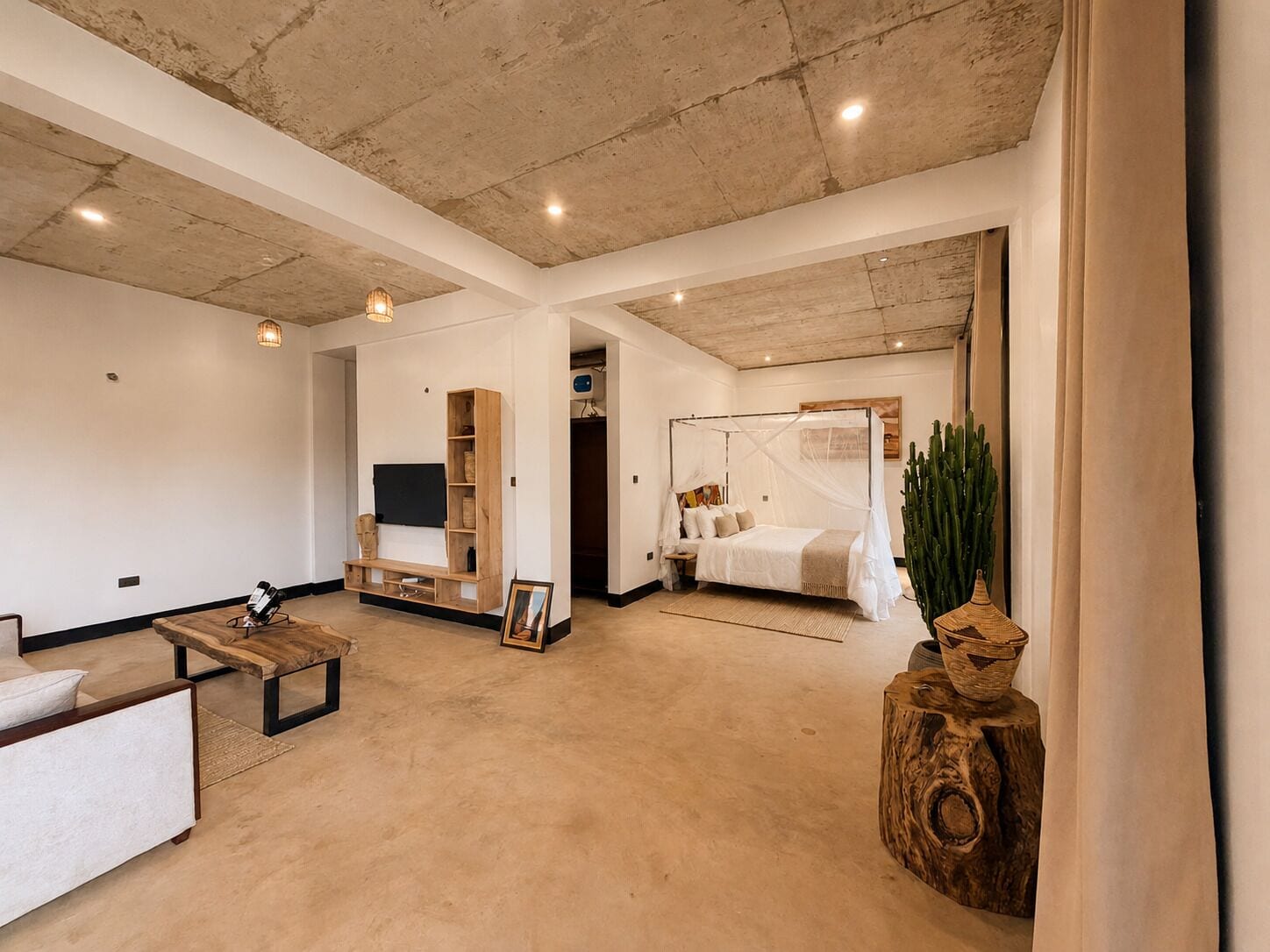 A spacious room with a large bed, a seating area with a sofa and a coffee table, and a television mounted on the wall.