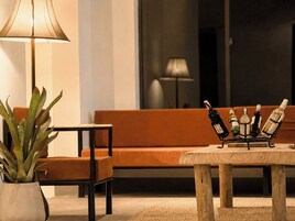 A cozy living area with a sofa, a table with a wine rack, and a lamp.