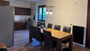 Een moderne keuken met houten kastjes, een inbouwoven en een eethoek met een houten tafel en zwarte stoelen.
