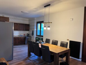 Eine moderne Küche mit Holzausstattung, integriertem Backofen und einem Essbereich mit Holztisch und schwarzen Stühlen.